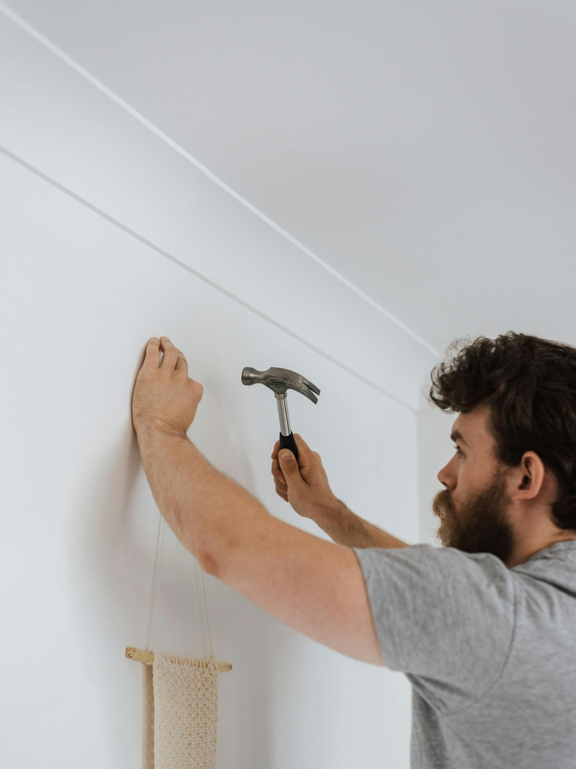 Handwerker hängt Dekoration mit Hammer im Wohnzimmer auf